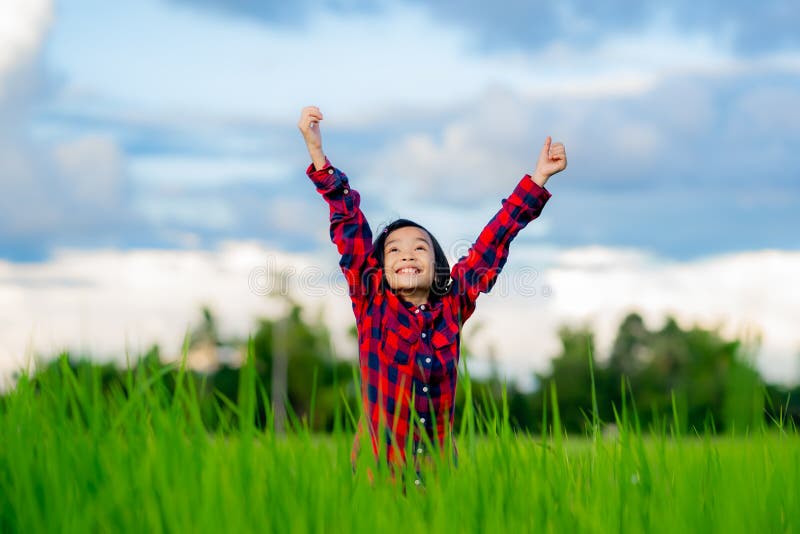 Happy children rise hand up to sky and smile in rice field of organic farmland