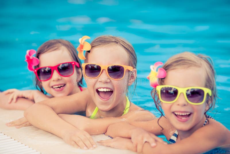 Happy children in the swimming pool. Funny kids playing outdoors. Summer vacation concept