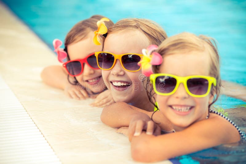 Happy children in the swimming pool. Funny kids playing outdoors. Summer vacation concept