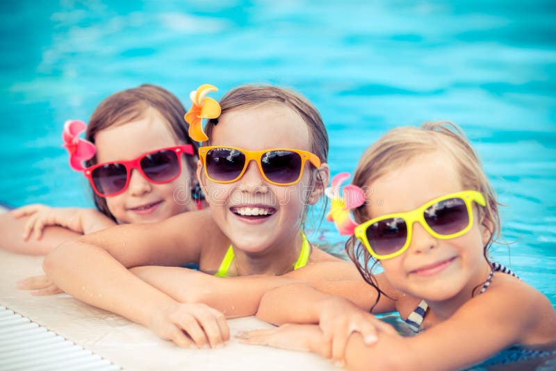 Happy children in the swimming pool. Funny kids playing outdoors. Summer vacation concept