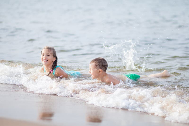 Happy children swimming in the sea, waves and splashes from swimming in the sea