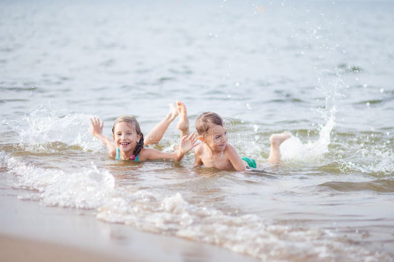 Happy children swimming in the sea, waves and splashes from swimming in the sea