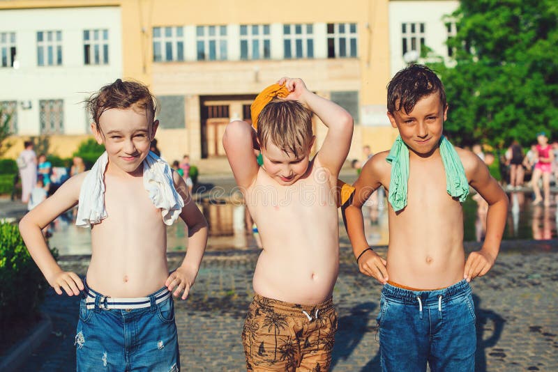 Children playing with a city fountain on hot summer day. Happy friends having fun outdoors. Summer weather