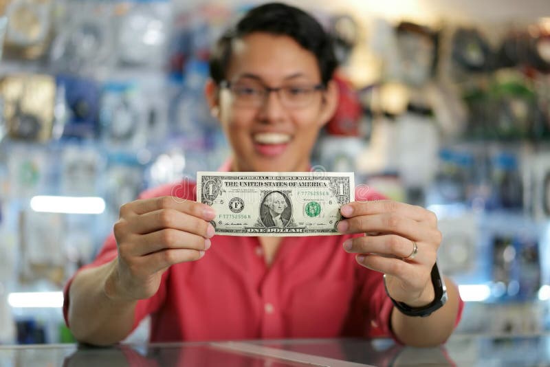 Mladý ázijský obchod majiteľ v počítač uchovávajte, zobrazené jeho prvý dolár na a.