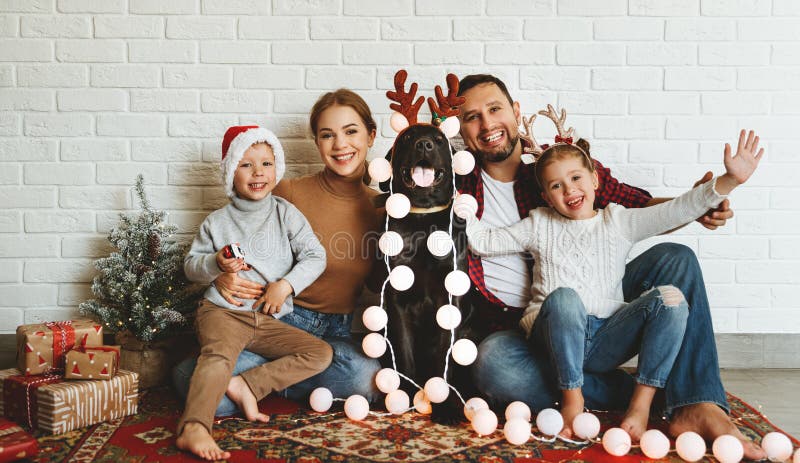 Happy Christmas! family mother father and kids with dog before Christmas with garland and tree stock photo Happy Christmas! family mother father and kids with dog before Christmas with garland and tree stock photo