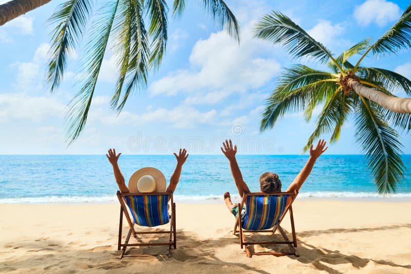 Happy couple with arms up relax on the beach enjoy beautiful sea on the tropical island