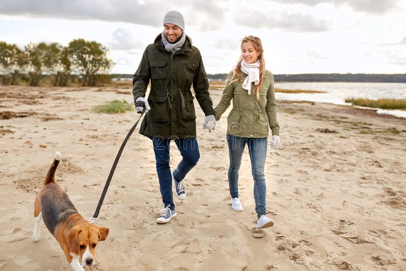 Happy couple with beagle dog on autumn beach