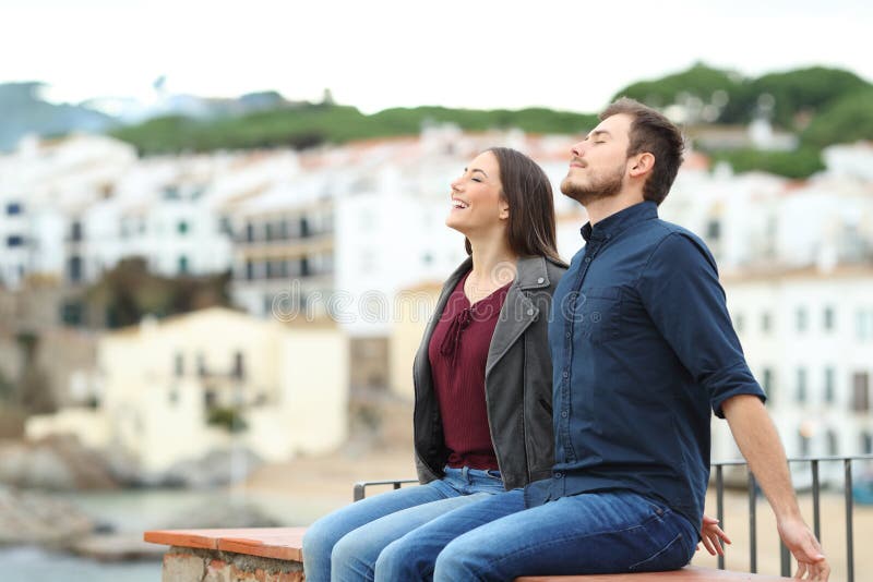 Happy couple breathing on a ledge on vacation