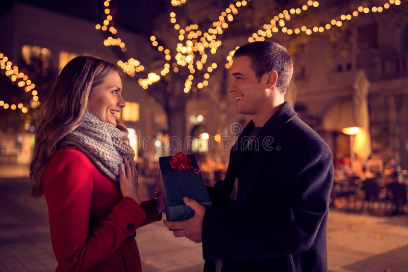 Happy couple with Christmas and New Year gift on street stock photo Happy couple with Christmas and New Year gift on street stock photo