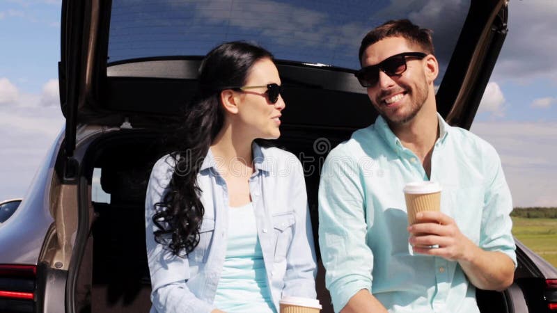 Happy couple with coffee at hatchback car trunk 11