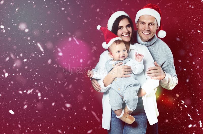 Happy couple with cute baby wearing Santa hats on red background, space for text. Magical Christmas atmosphere stock photos