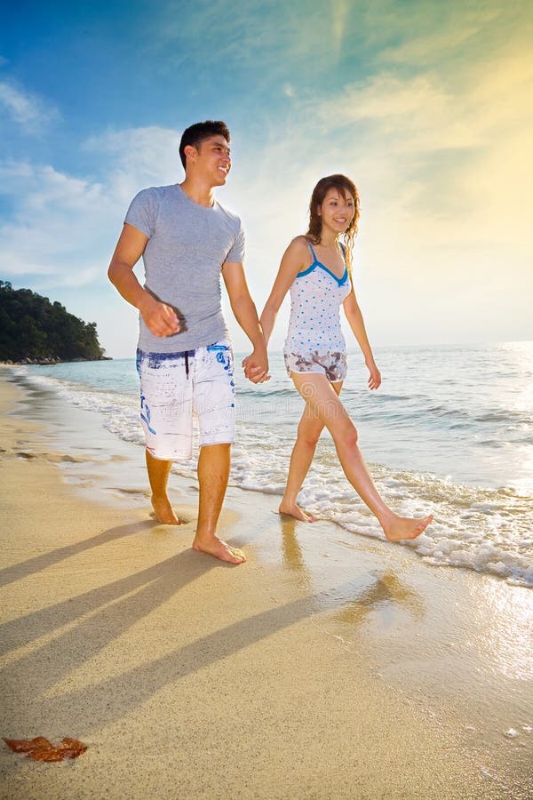 Happy couple enjoying walking along sunset beach