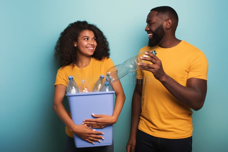 Happy couple hold a plastic container with bottles over a light blue color. Concept of ecology, conservation, recycling royalty free stock photography Happy couple hold a plastic container with bottles over a light blue color. Concept of ecology, conservation, recycling royalty free stock photography