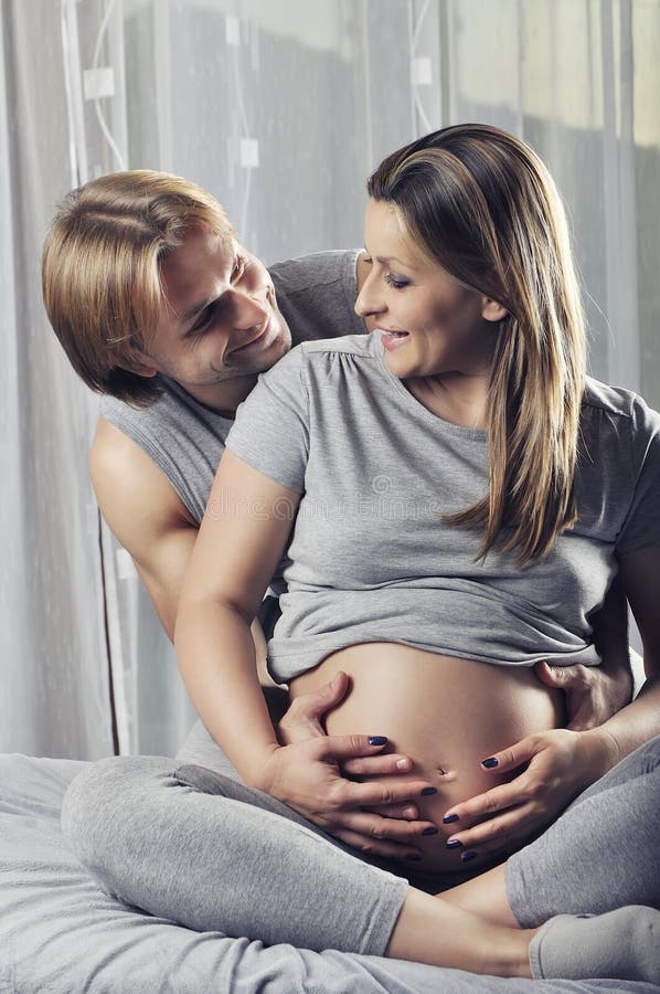 Happy couple holding pregnant belly and smile