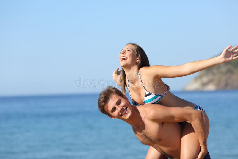 Happy couple joking celebrating vacation on the beach