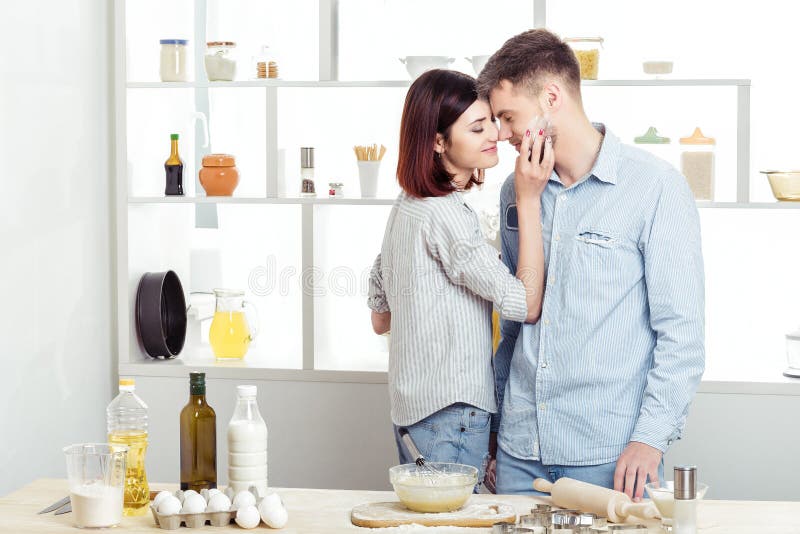 Happy Couple in love cooking dough and kissing in kitchen stock image Happy Couple in love cooking dough and kissing in kitchen stock image