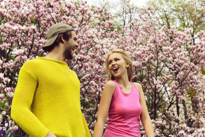 Happy couple in love in spring magnolia flowers, smiling men and girl in garden with blossom tree outdoor on natural background