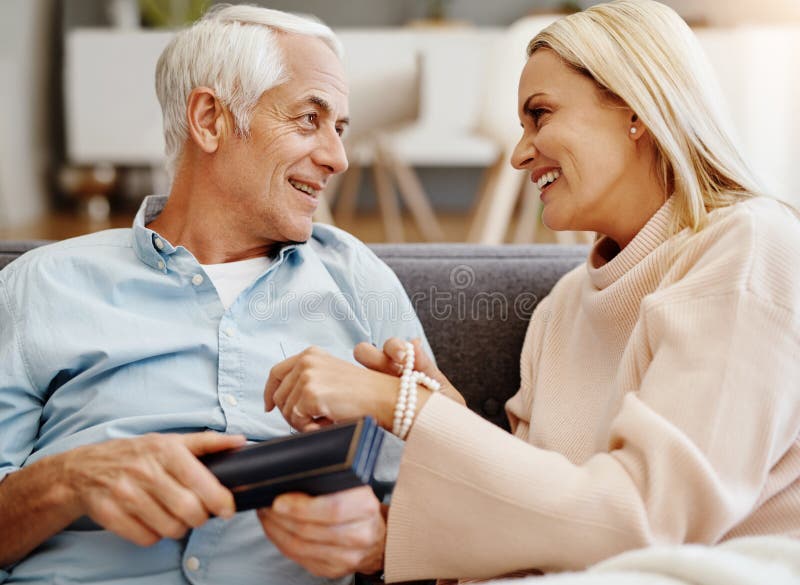 Happy couple, mature and jewelry in home for gift, love and romantic gesture in living room. Woman, man and birthday royalty free stock photography