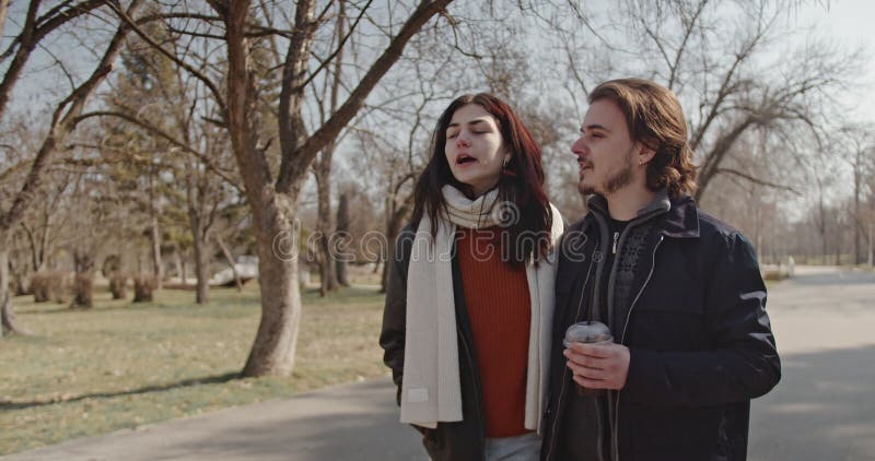 Happy Couple profite d'une promenade ensoleillée dans le parc avec des boissons chaudes banque de vidéos