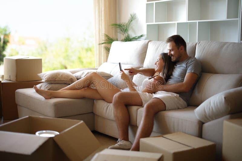 Happy couple resting while moving home checking phone royalty free stock photo