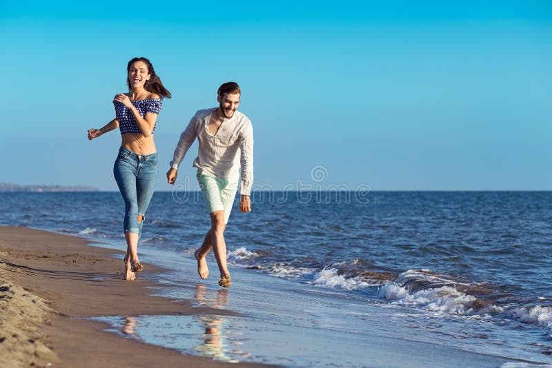 Happy couple running on the beach. Attractive, girlfriend.