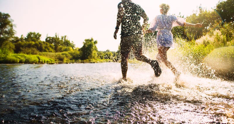 Happy couple running in shallow water stock image