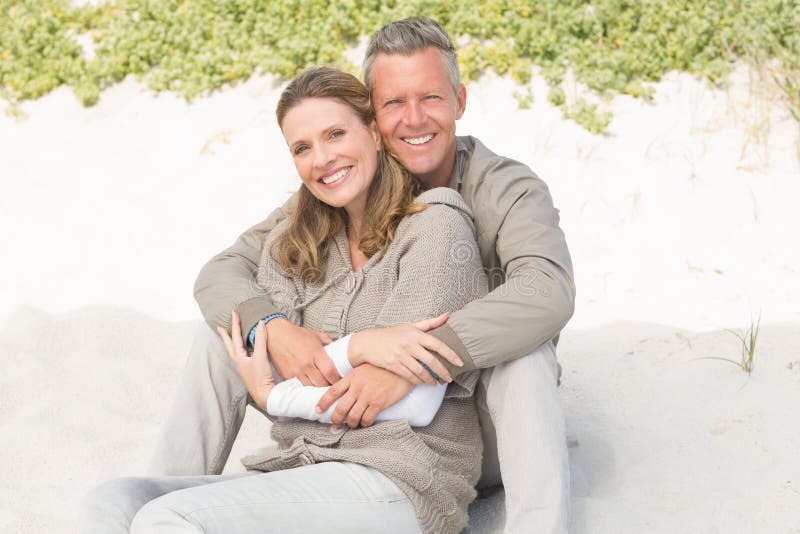 Happy couple sitting on the sand stock image Happy couple sitting on the sand stock image