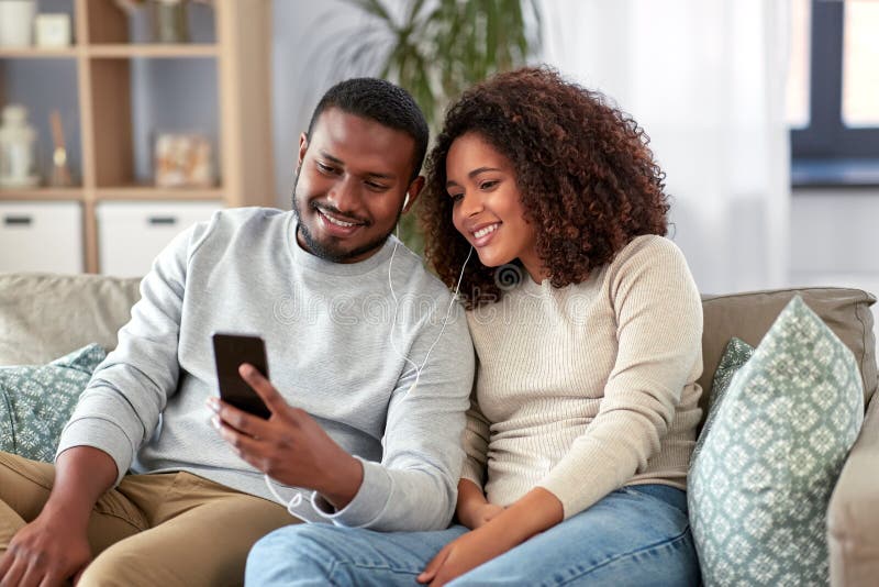 Happy Couple with Smartphone and Earphones at Home Stock Photo - Image ...