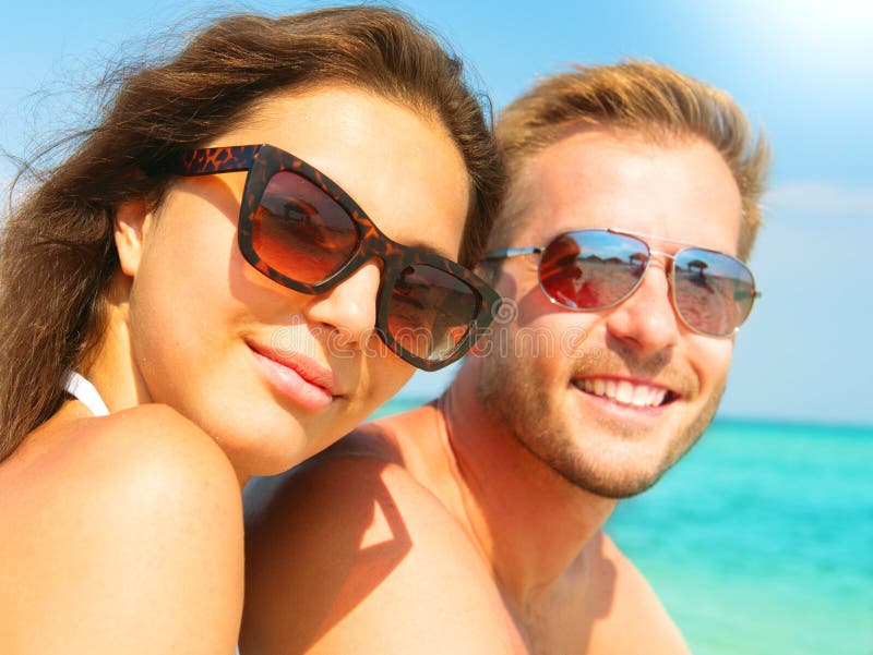 Happy couple in sunglasses on the beach stock photo Happy couple in sunglasses on the beach stock photo