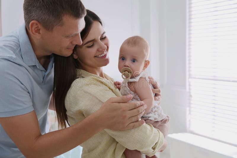 Happy couple and their cute little baby with pacifier at home stock image