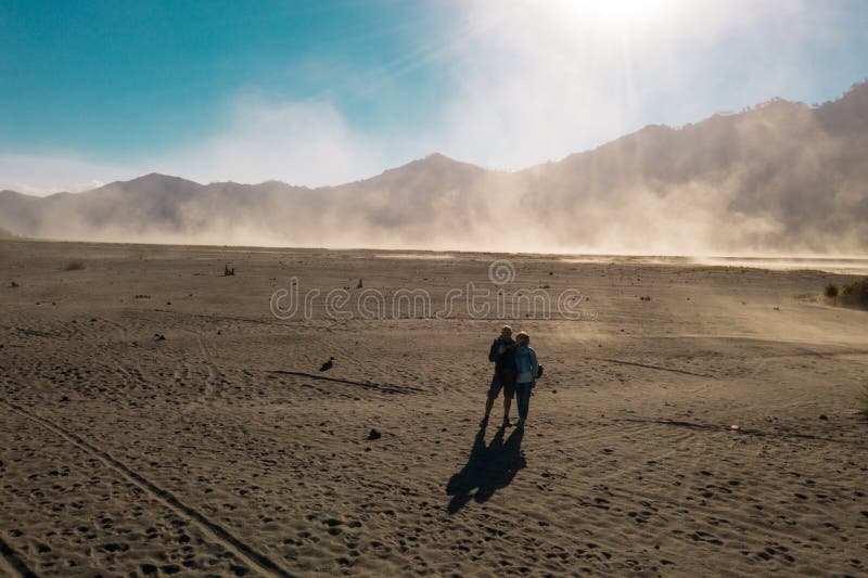 Happy couple travelers standing in a volcanic dusty desert near beautiful Mount Bromo in East Java. Indonesia stock photos Happy couple travelers standing in a volcanic dusty desert near beautiful Mount Bromo in East Java. Indonesia stock photos
