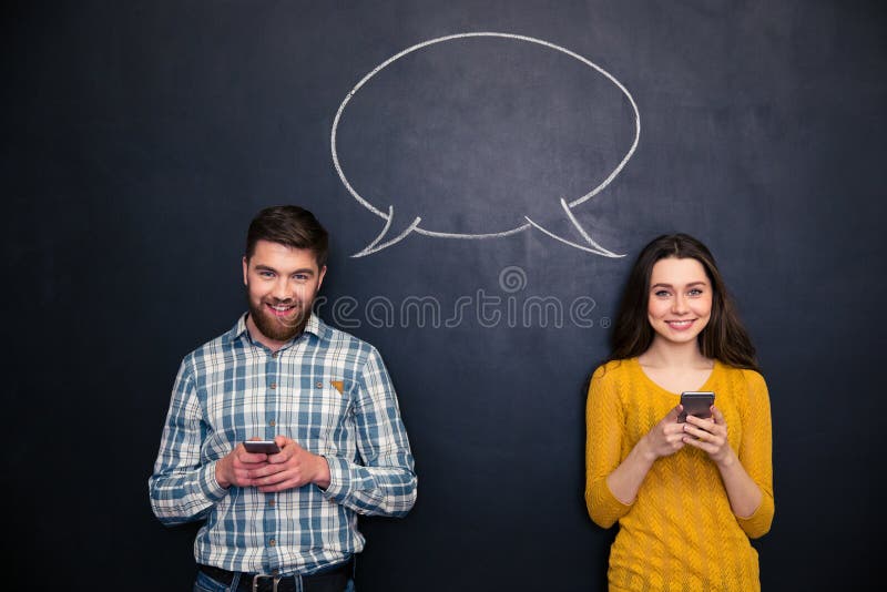 Happy couple using mobile phones over chalkboard with speech bubble stock photography Happy couple using mobile phones over chalkboard with speech bubble stock photography