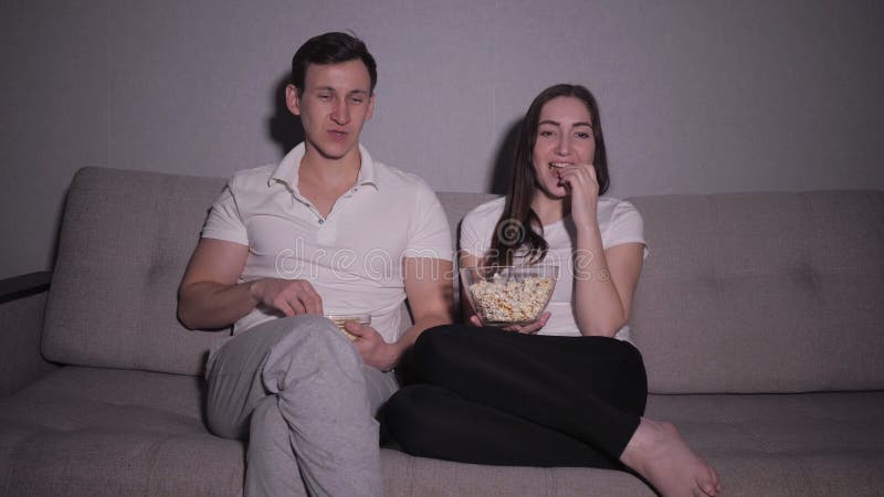 Happy couple watching a movie on tv sitting on a couch at home