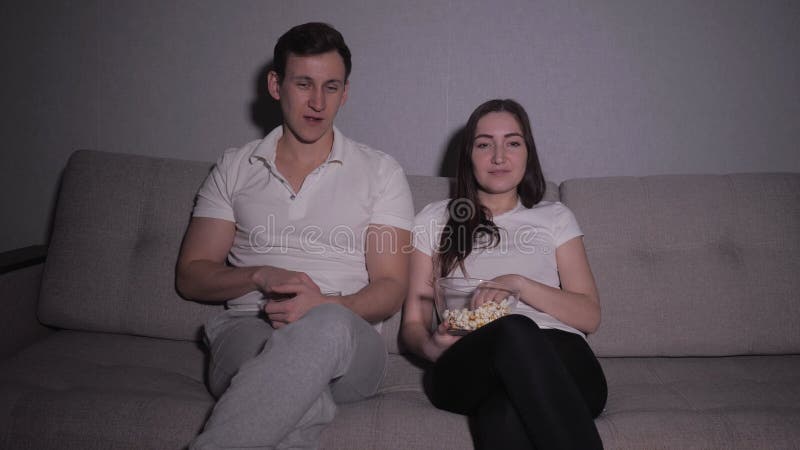 Happy couple watching a movie on tv sitting on a couch at home