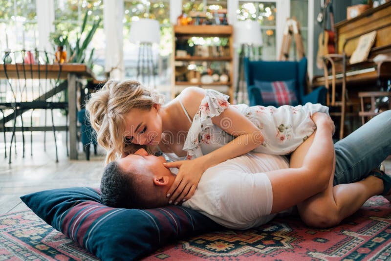 Happy couple of young lovers lying on floor on carpet and relax