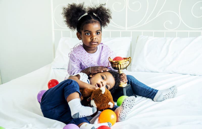 A Happy cute active little african american kids boy and girl relaxing on bed at home