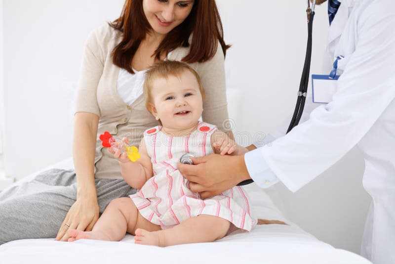 Happy cute baby with her mother at health exam at doctor`s office.