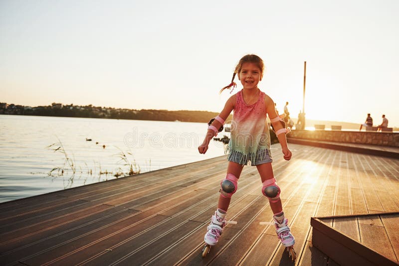 Happy cute kid riding on her roller skates. Summertime leisure and weekends