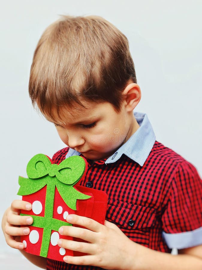 Happy cute little kid holding red gift box isolated over the white background royalty free stock photo Happy cute little kid holding red gift box isolated over the white background royalty free stock photo