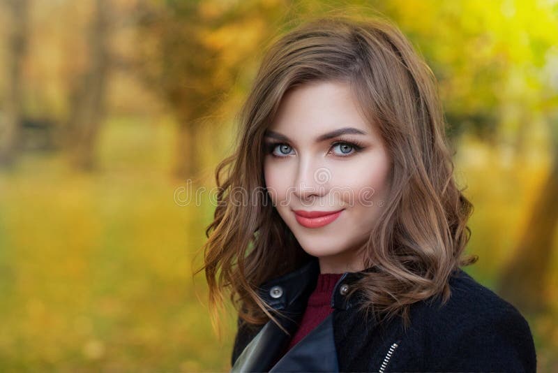 Happy cute young woman in park on sunny autumn day