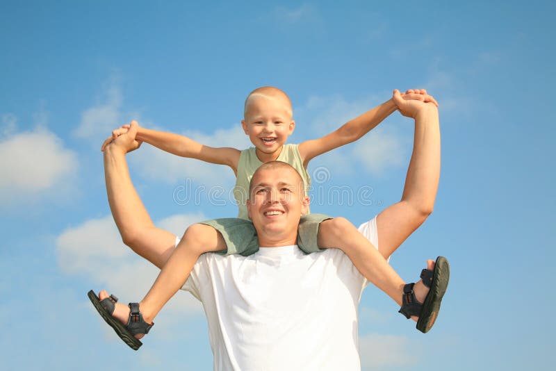 Happy dad with his son, smiling at the blue sky