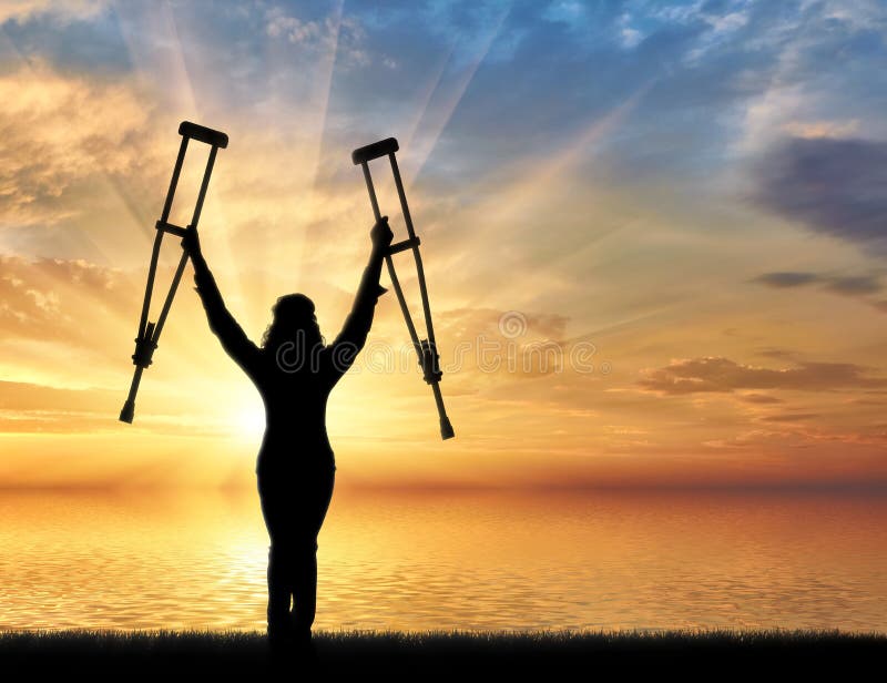 Happy Disabled on Beach and Holding His Crutches Sunset Stock Photo
