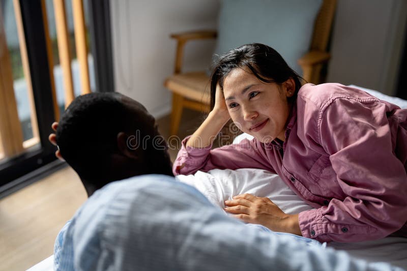 Happy and diverse couple sharing a joyful moment at home, embracing and smiling together stock photos