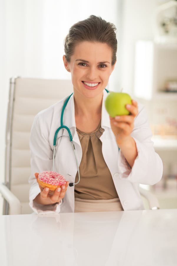 Happy doctor woman giving apple instead of donut royalty free stock image Happy doctor woman giving apple instead of donut royalty free stock image