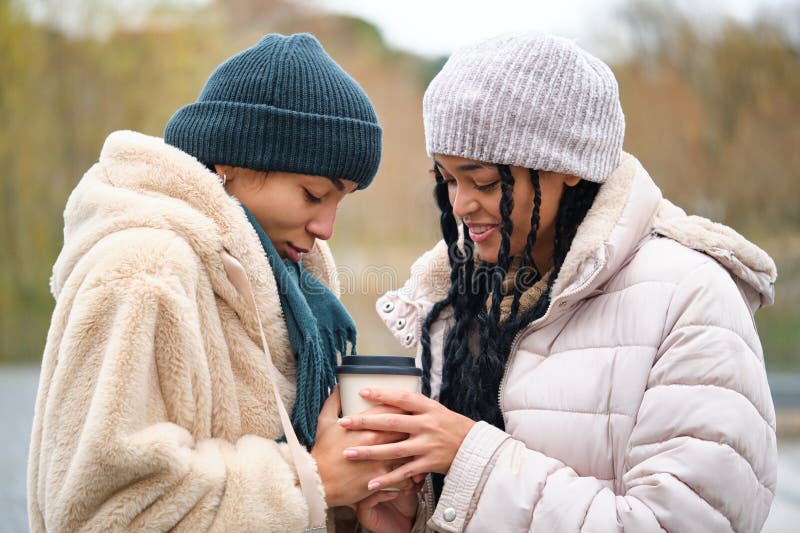 Happy Dominican Lesbian Couple With A Coffee Cup At Street In A Cold