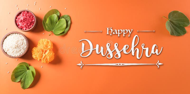 Happy Dussehra. Yellow flowers, green leaf and rice on orange background. Dussehra Indian Festival concept royalty free stock photo