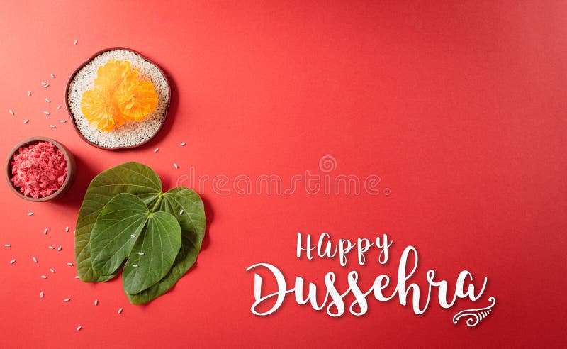 Happy Dussehra. Yellow flowers, green leaf and rice on red background. Dussehra Indian Festival concept stock photo