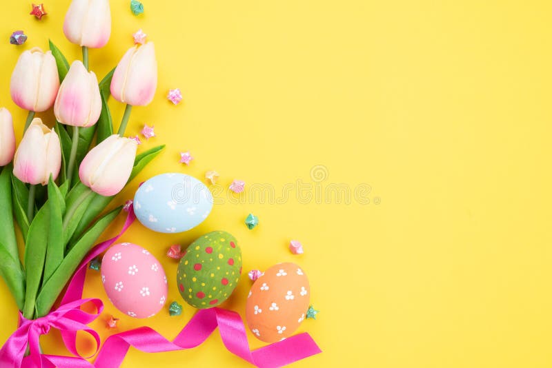 Happy easter! Colourful of Easter eggs in nest with pink tulip flower and Feather on yellow paper background