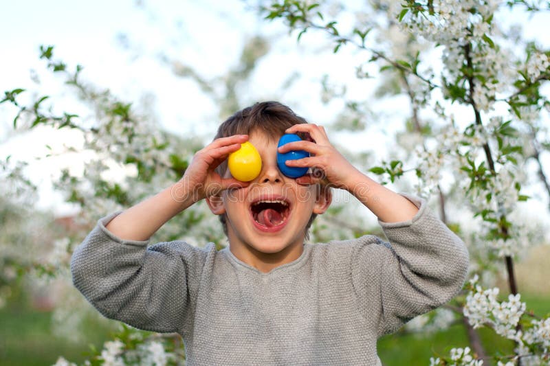 Happy easter. Cute funny preschooler boy with Easter eggs in garden. Laughing child during an Easter egg hunt.