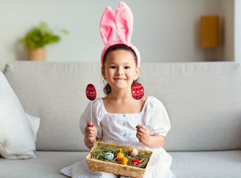 Asian Girl Wearing Easter Bunny Ears Posing Holding Eggs Indoors